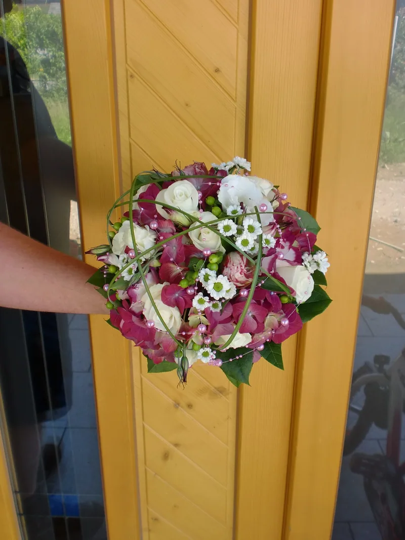 Brautstrauß aus Rosen und Margeriten vor einer Holztür