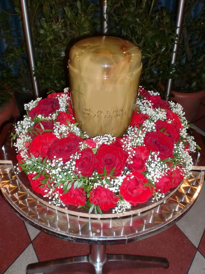 Urnenschmuck aus roten Rosen rund um eine Urne